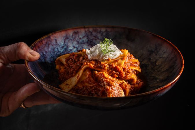 Gourmet Italian pasta with rich meat sauce and ricotta in ceramic bowl