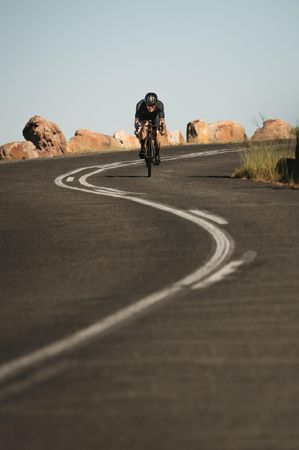Cyclist cycling down hill on a curvy mountain road
