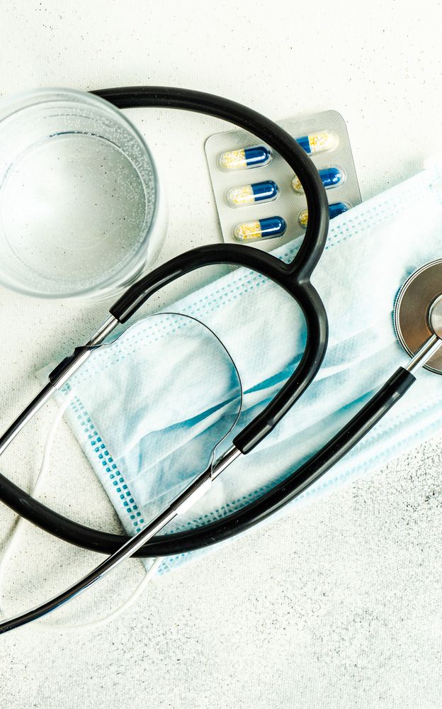 Top view of pills, facemask and stethoscope, vertical