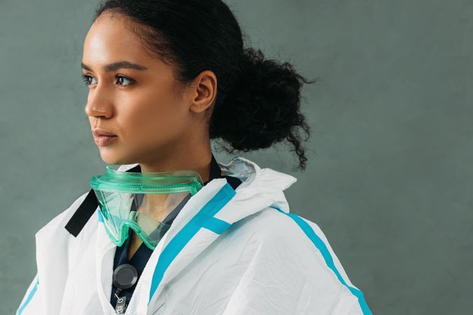 Side view of Black female medical worker with PPE goggles around her neck