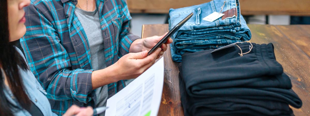 Banner of unrecognizable woman holding digital tablet while checking clothes stock on local store