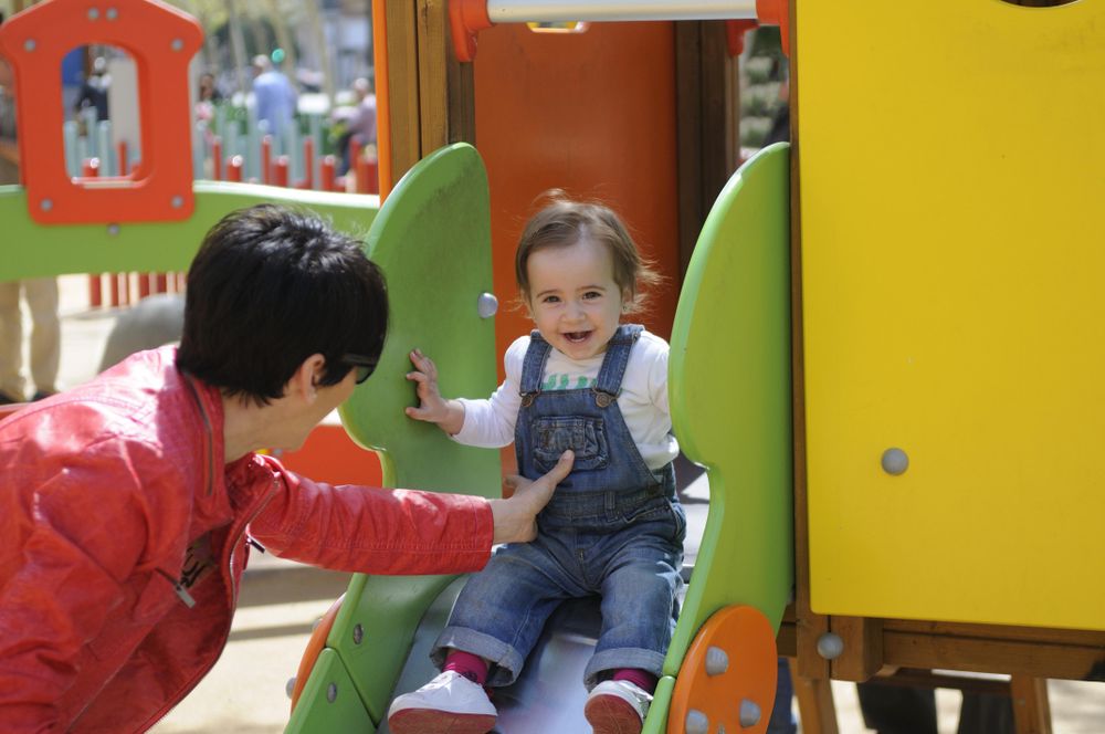 Woman helping her daughter down a slide