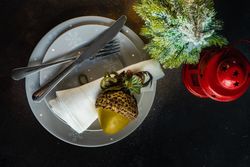 Top view of holiday table setting on grey plates with ornamental hazelnut and red lantern