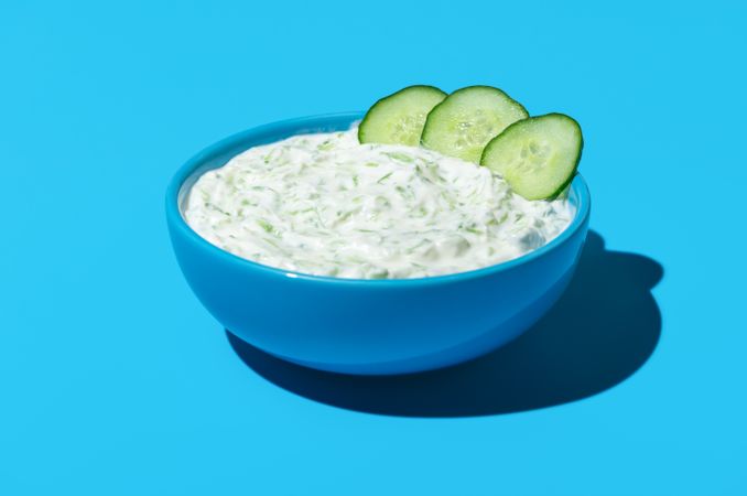Tzatziki sauce bowl isolated on a blue colored background
