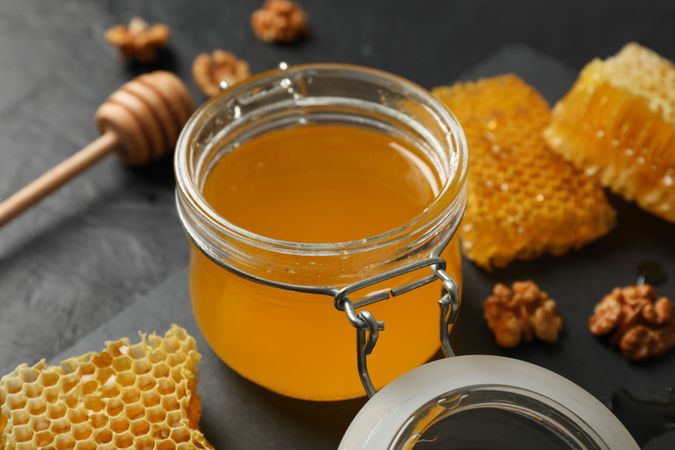 Walnut, honeycombs, jar with honey and dipper on dark background, closeup