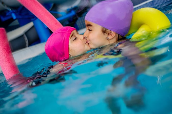 Sisters kissing in swimming pool