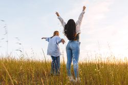 two women friends enjoying in a field at sunset