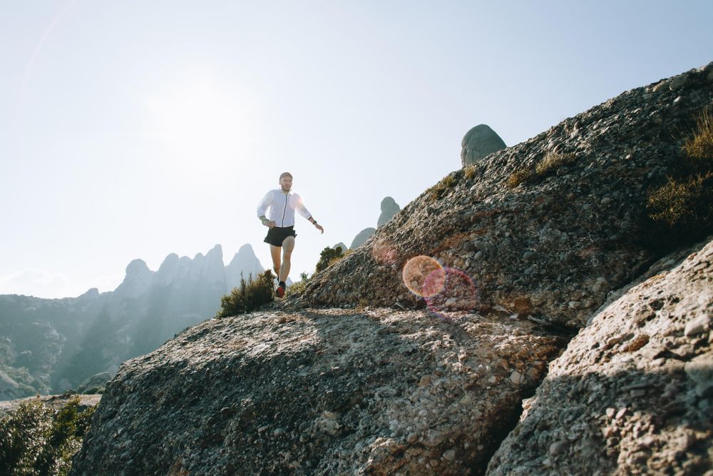 Male running on a rocky terrain with sunflare