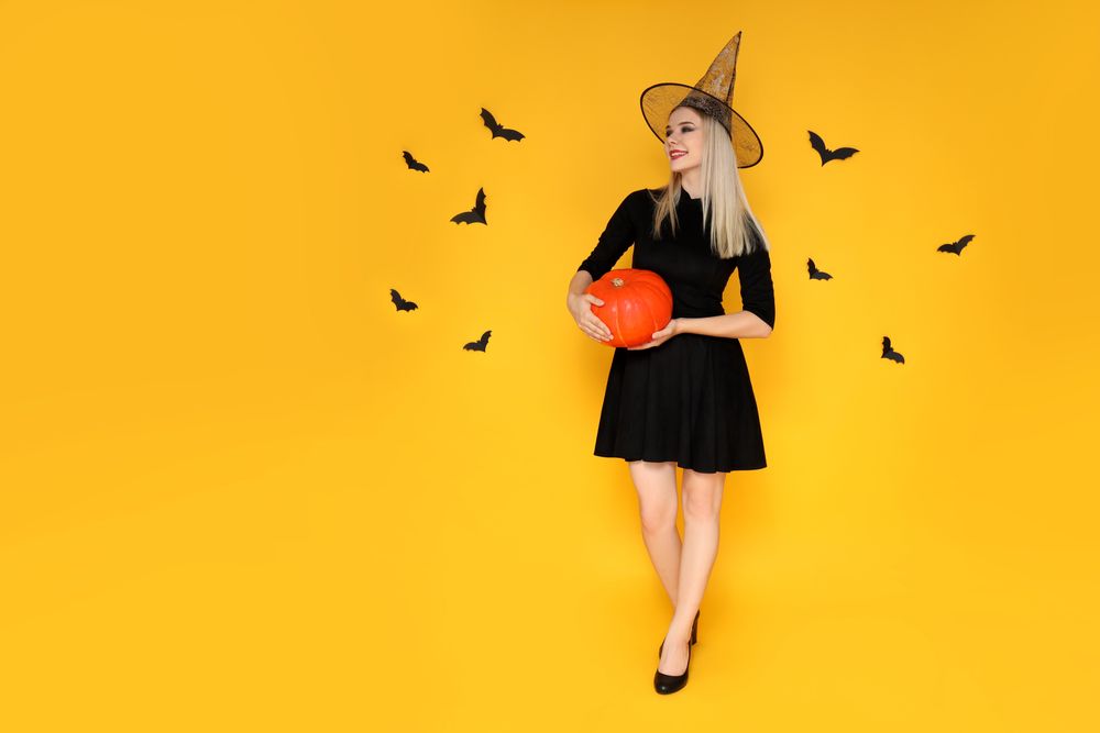 Concept of Halloween, young woman on yellow background