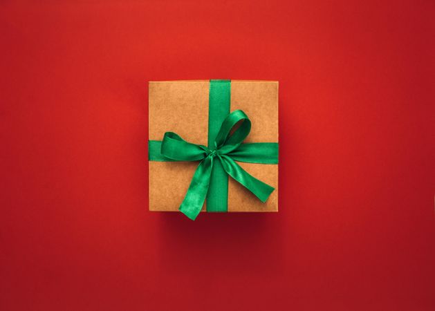 Present box with green ribbon bow on colorful background