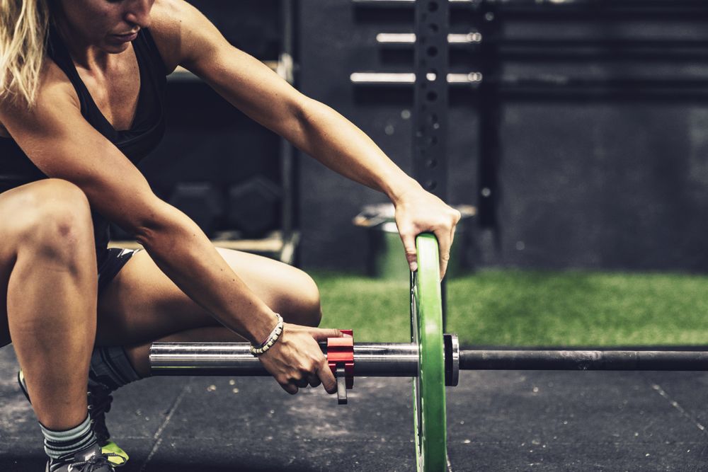 Concentrated female fixing barbell before workout