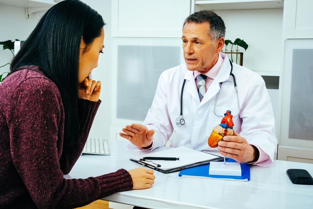 Male doctor with female patient showing heart model