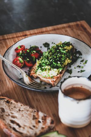 Avocado toast on sourdough bread, with cherry tomatoes and coffee