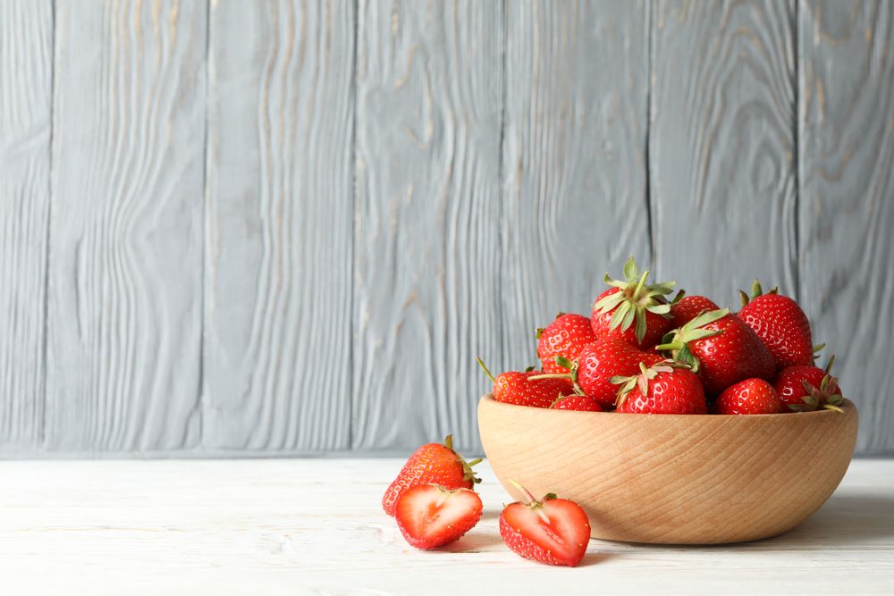 Bowl with tasty strawberry on wooden table. Summer berry
