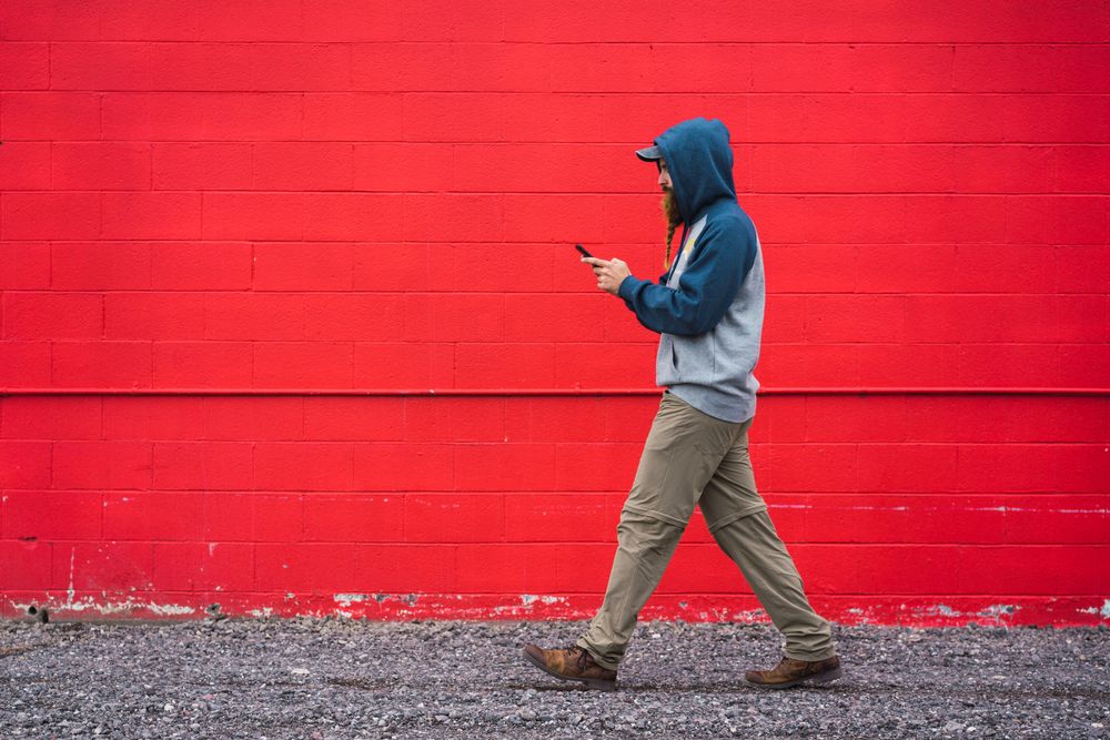 Man using smartphone near red wall