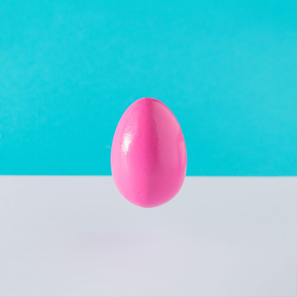 Pink egg suspended on blue background