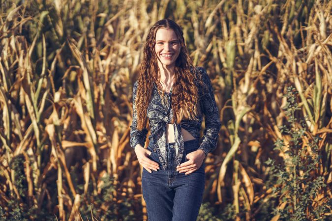 A Smiling Woman Standing in a Cornfield During the Beautiful Golden Hour of the Day