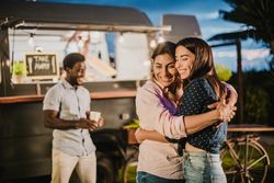 Cheerful girlfriends hugging near food truck