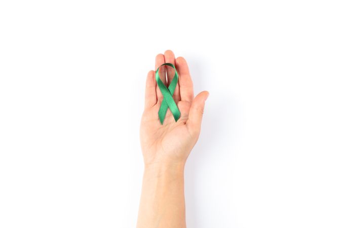 Female hand with green awareness ribbon isolated on blank background