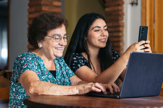 Grandmother and granddaughter using laptop at home