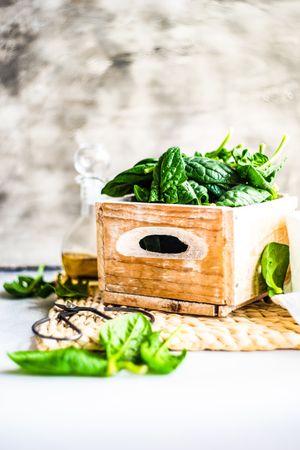 Box of spinach leaves on rattan placemat