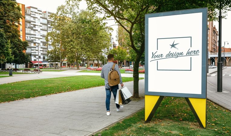 Man walking beside a customizable advertising poster