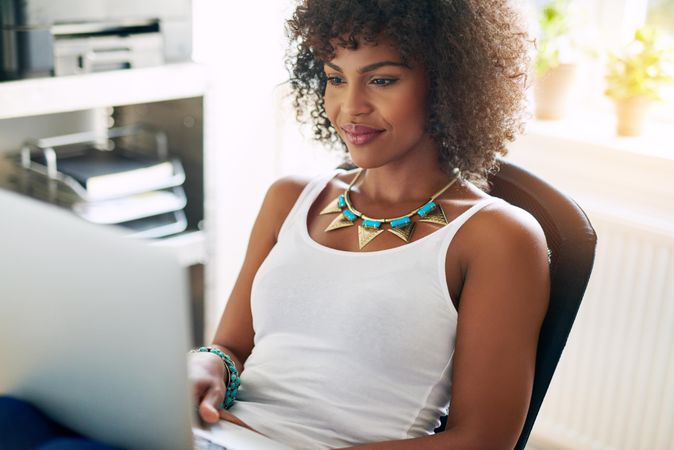 Female entrepreneur sitting in front of her laptop in bright home office
