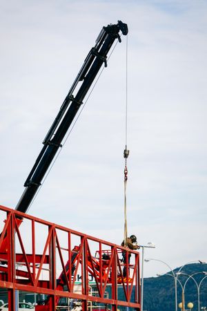 Man standing at billboard frame beside a crane