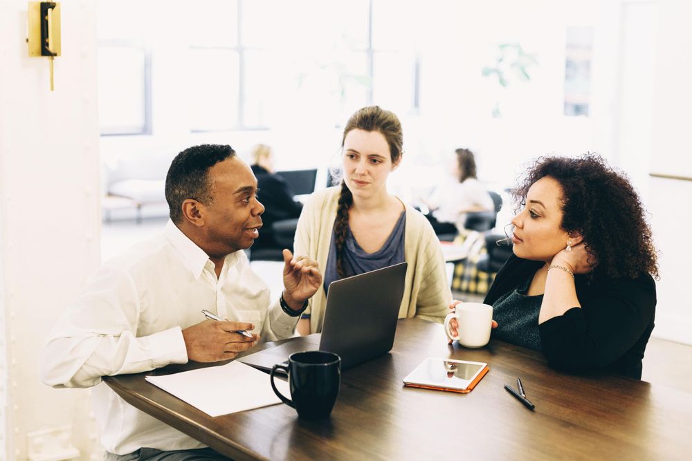 Man and two women sitting and talking in meeting room