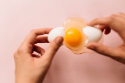 Unrecognizable person breaking chicken egg on table