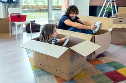 Father and son playing car racing with cardboard boxes