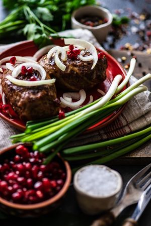 Top view of Georgian abkhazura cutlets on plate with spring onions & pomegranate seeds