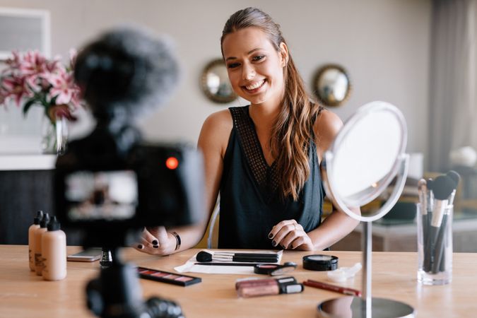Woman making video for her blog with makeup products