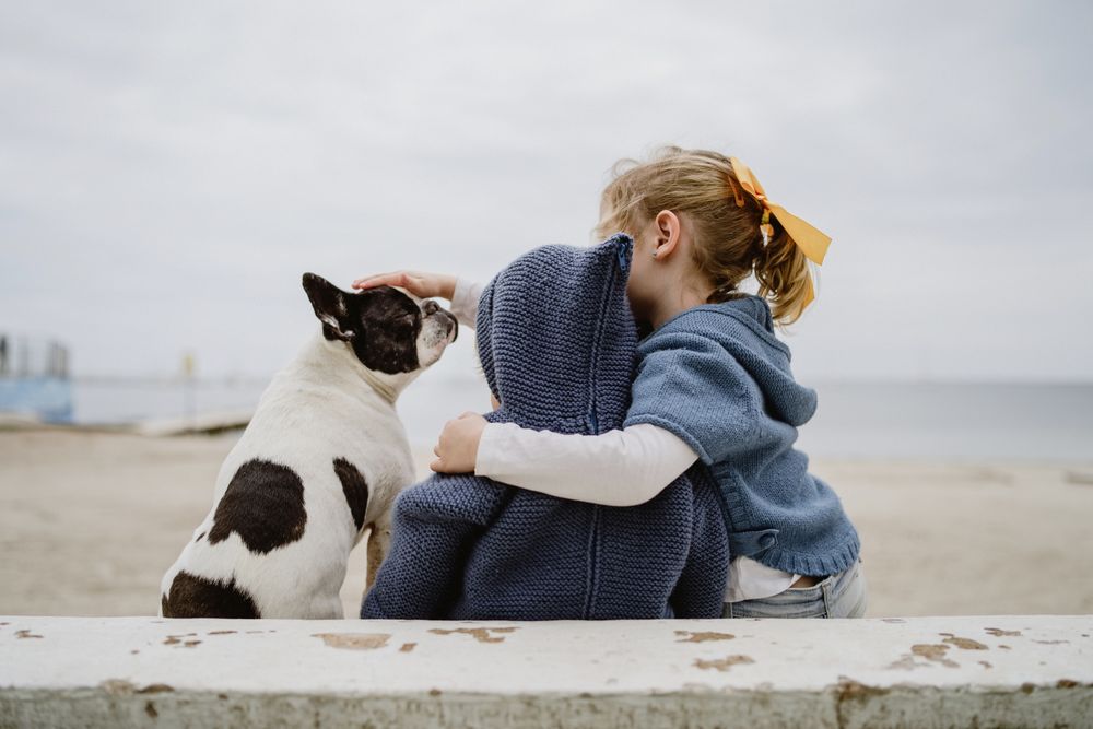 Kids hugging dog on beach
