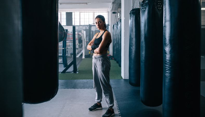 Female boxer surrounded by punching bags in studio