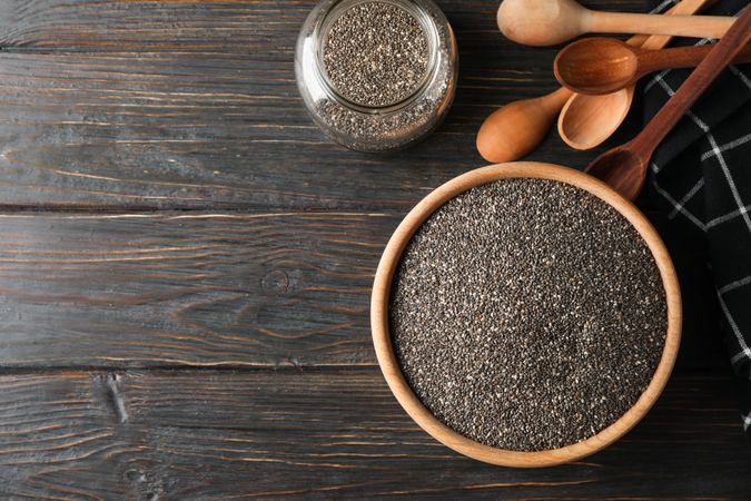 Chia in wooden bowl on wood background, top view