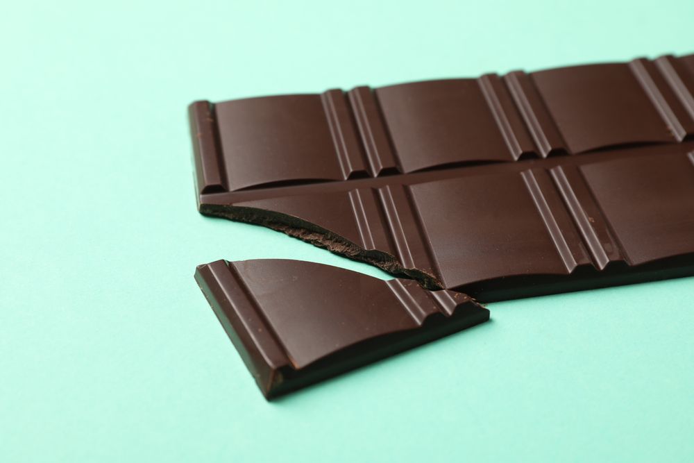 Tasty chocolate bar on mint background. Sweet food