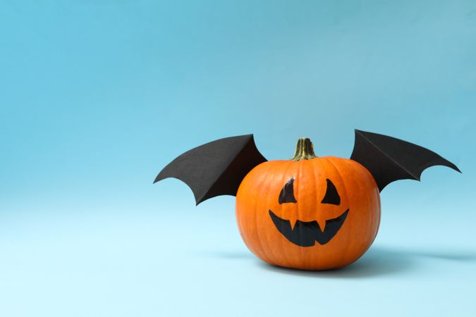 Pumpkin with smile and wings on blue background