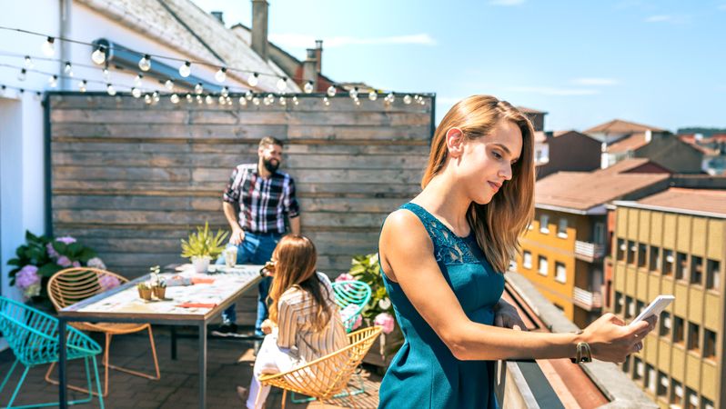 Young woman with green dress looking mobile on rooftop