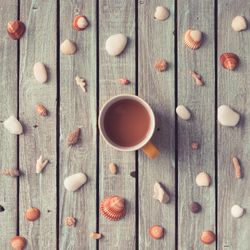 Summer morning coffee surrounded by pattern made of sea shells and rocks