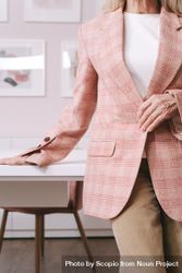 Woman in pink plaid blazer standing beside light desk indoor bx6rd5