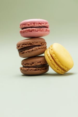 Chocolate, strawberry & lemon macaroons on a green table, vertical