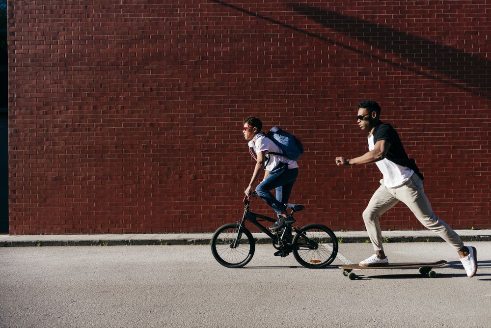 Young Black men riding bicycle and skateboard