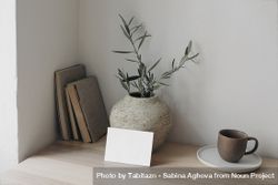 Wooden table with vase of eucalyptus branches, books and mug with mockup card 0J3RZ5