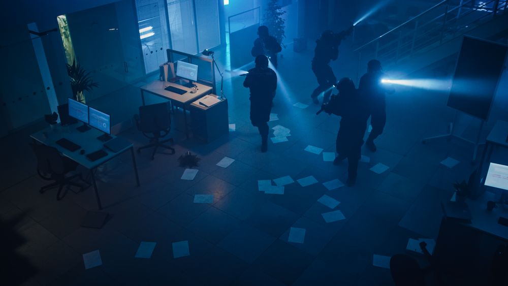 Masked Squad of Armed SWAT Police Officers Storm a Dark Seized Office Building with Desks and Computers.