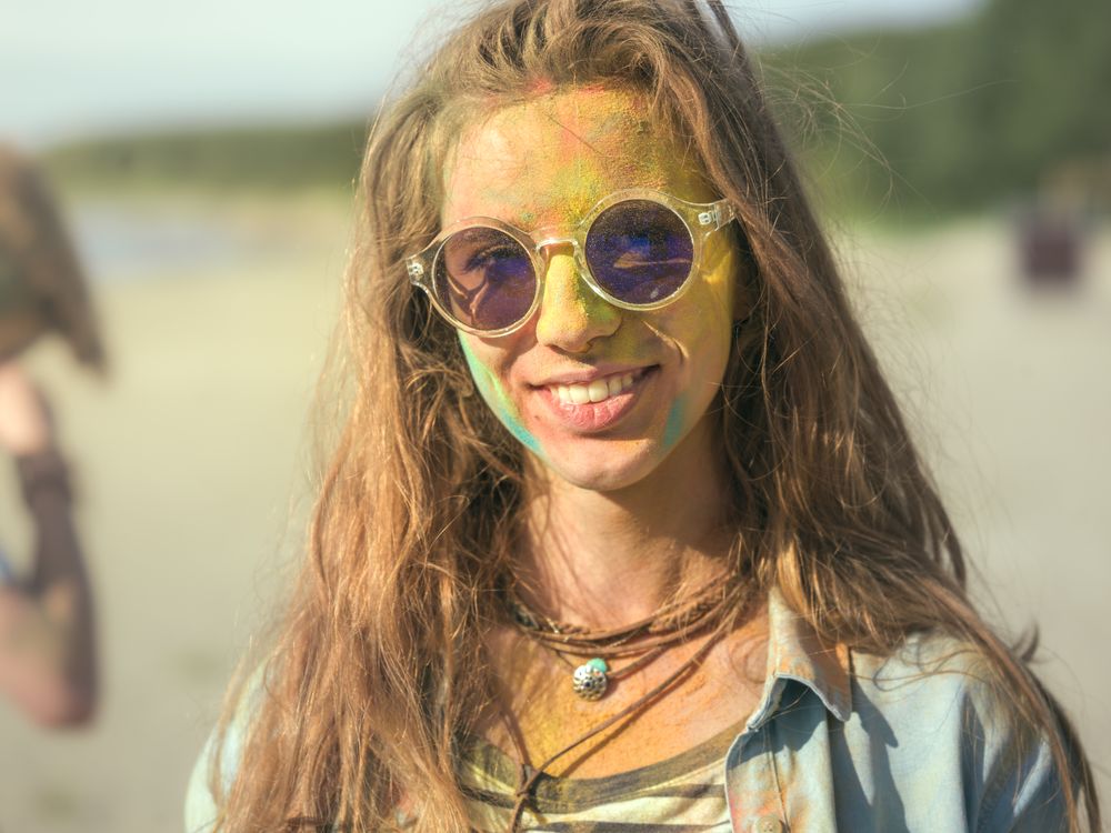Close-up Portrait of a Young Woman with Sunglasses Standing in the Crowd of People Celebrating Holi Festival.