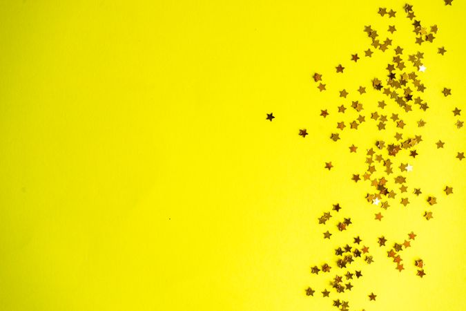 Festive xmas card concept of star glitter on yellow background