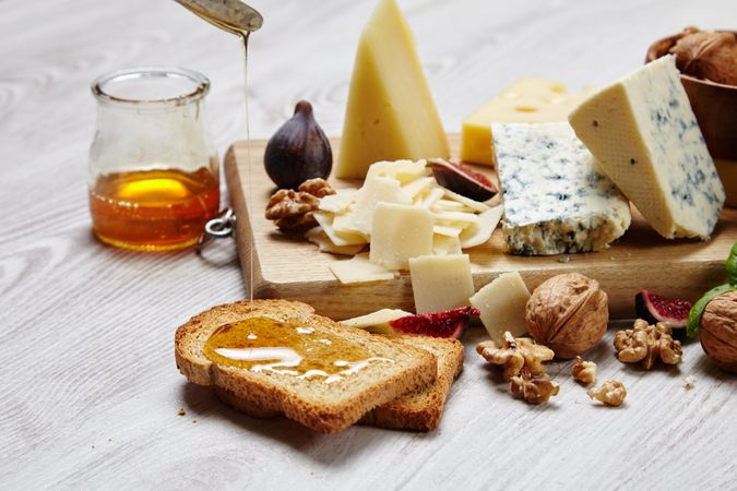 Cheese plate on wooden board with toast and honey, landscape