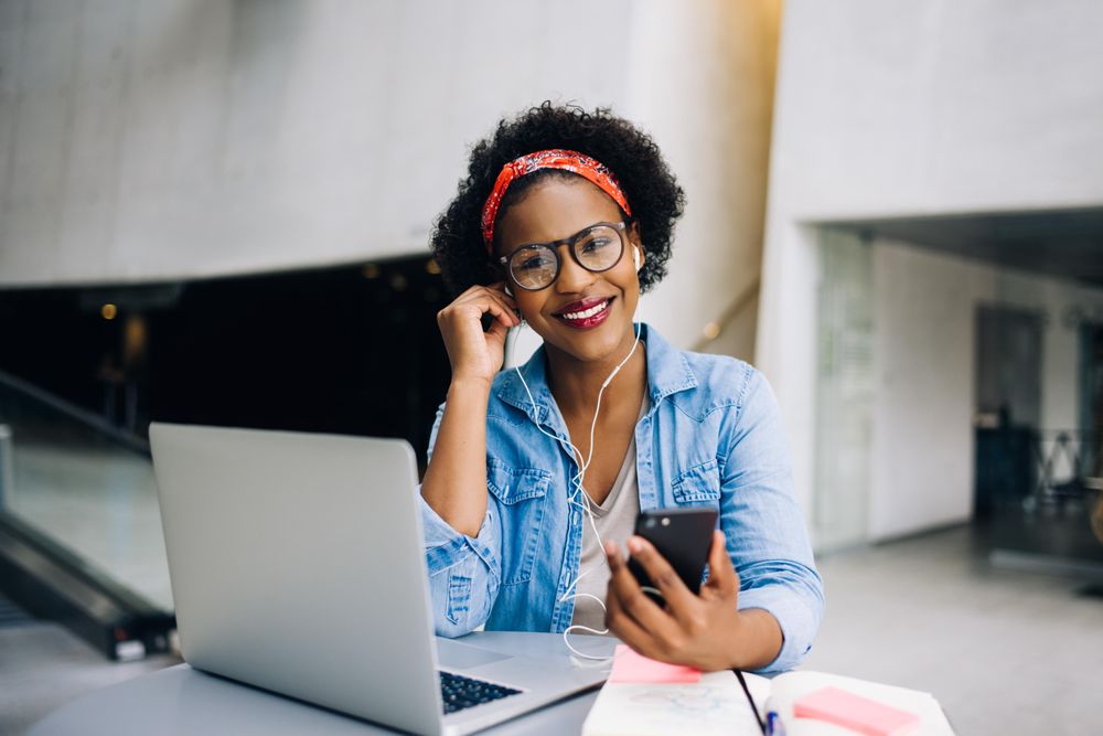 Woman listening to music in headphones from her phone at work in an open office