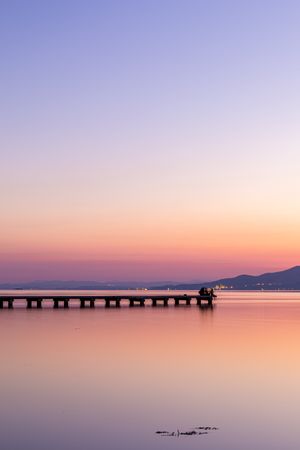 Anonymous tourists on pier during sundown